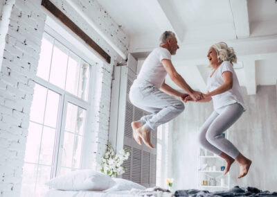 Senior couple jumping on bedding australia bed