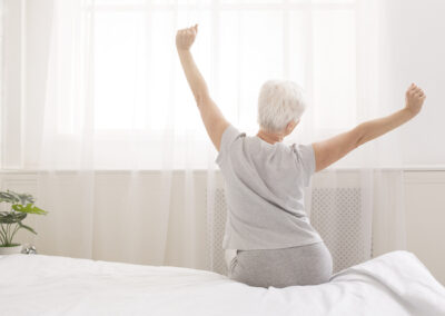 Senior woman sitting on her bedding Australia bed in morning
